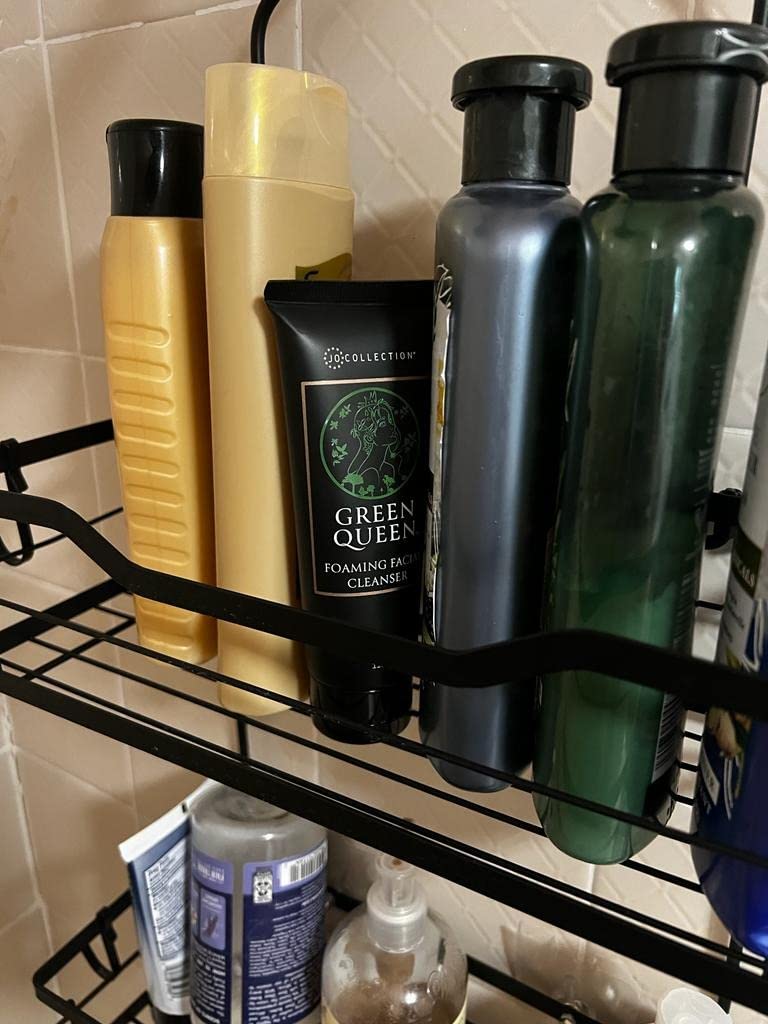 Shelf with various skincare products including bottles and a tube on a tiled bathroom wall.