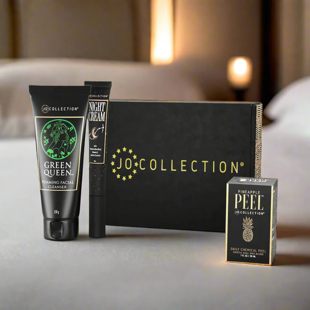 JO Collection skincare products including a tube of 'Green Queen' cleanser and 'Night Cream', a black box, and a small box labeled 'Pineapple Peel'.