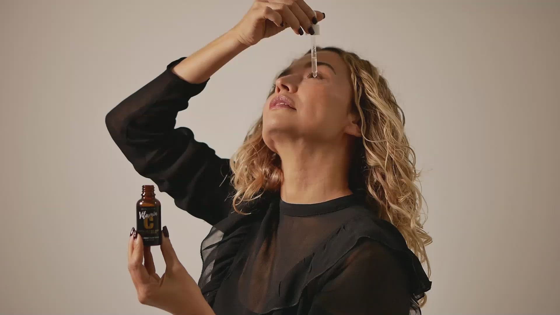 woman applying Jo Collection Vitamin C with hyaluronic acid and vitamin e to her face with a dropper