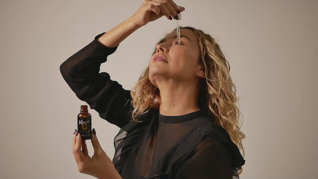 woman applying Jo Collection Vitamin C with hyaluronic acid and vitamin e to her face with a dropper